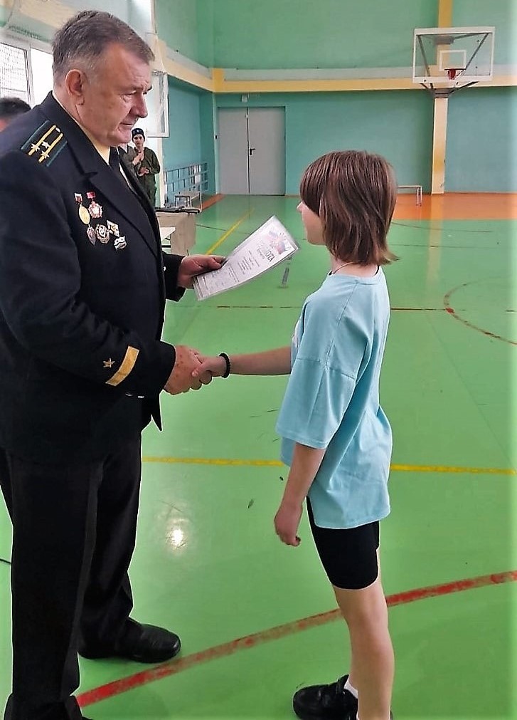  Представитель Российского фонда ветеранов в Сочи капитан 1 ранга в отставке Виталий Ковалёв вручает грамоту победителю.