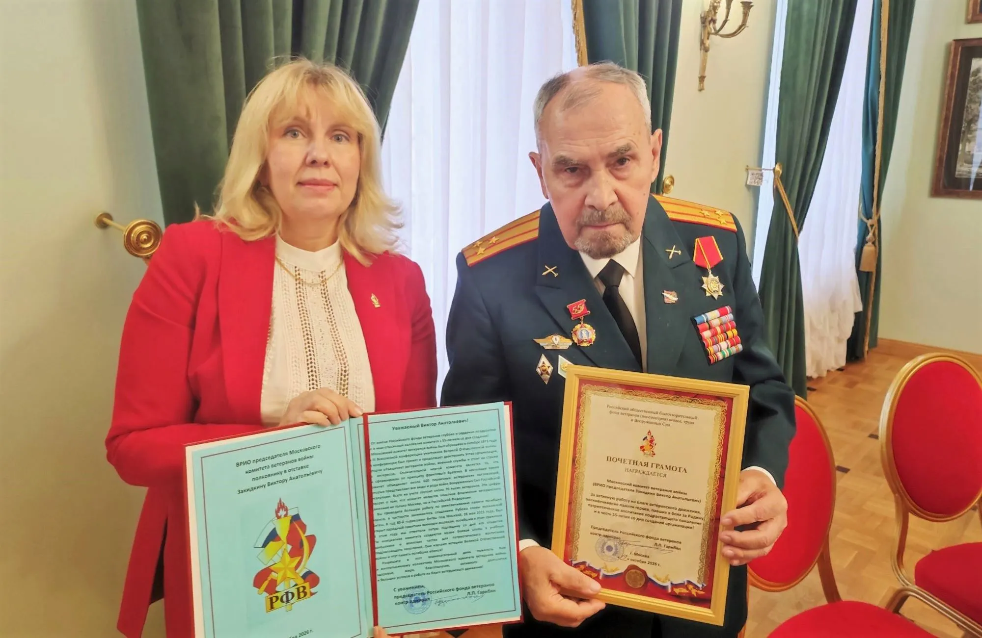 На снимке помощник председателя Российского фонда ветеранов, секретарь Правления Фонда Маргарита Сидорова вручает Почётную грамоту и поздравительный адрес ВрИО председателя Комитета ветеранов войны Виктору Закидкину.